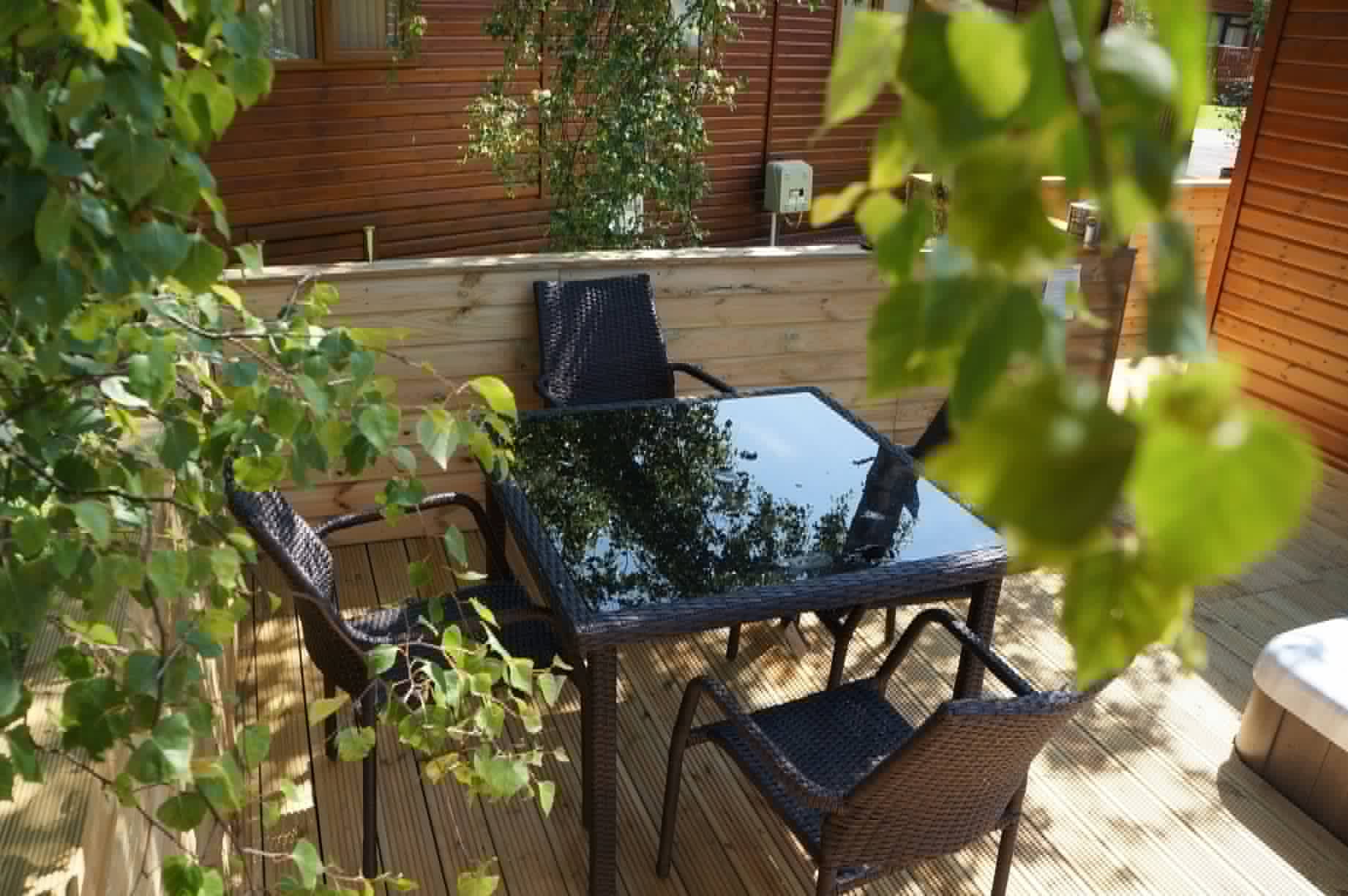 Private lodge decking seating area surrounded by timber screening